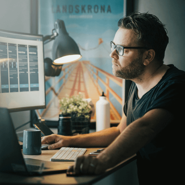 Man focused at computer desk with modern setup, relaxes due to simple web design and tech support